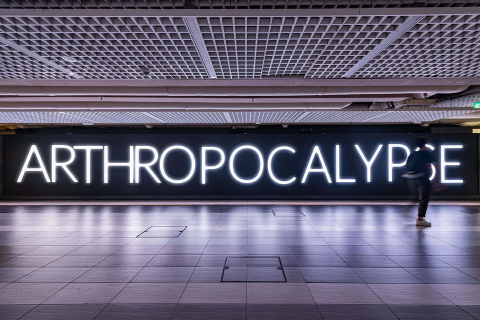 LED screen in a corridor displaying the word 'Arthropocalypse'.