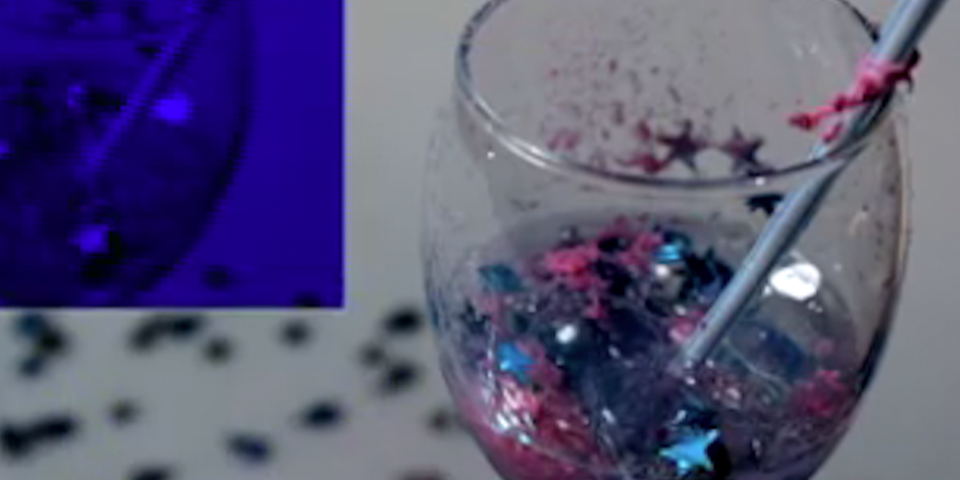 A cup filled with glitter on the right, and a blue square on the left.